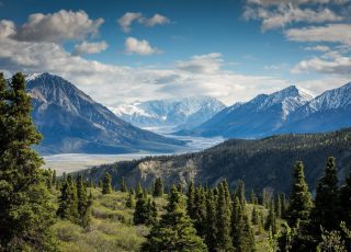 snow capped mountains with valley and forest