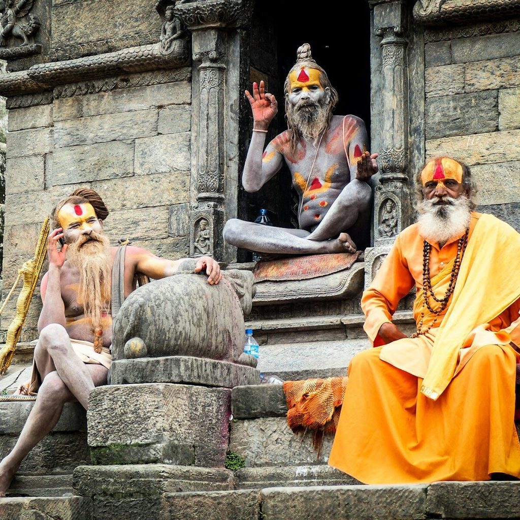 three monks sitting on concrete temple during daytime
